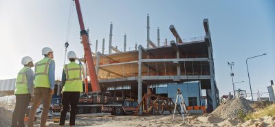 An example picture of three people looking at a construction site of a building to show what commercial loans can be used for.