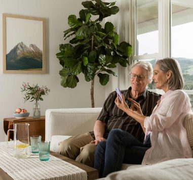 A mature couple looking together at one cell phone. Indicates that Zelle can be used easily.